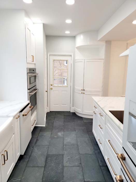 A kitchen with white cabinets and black tile floors