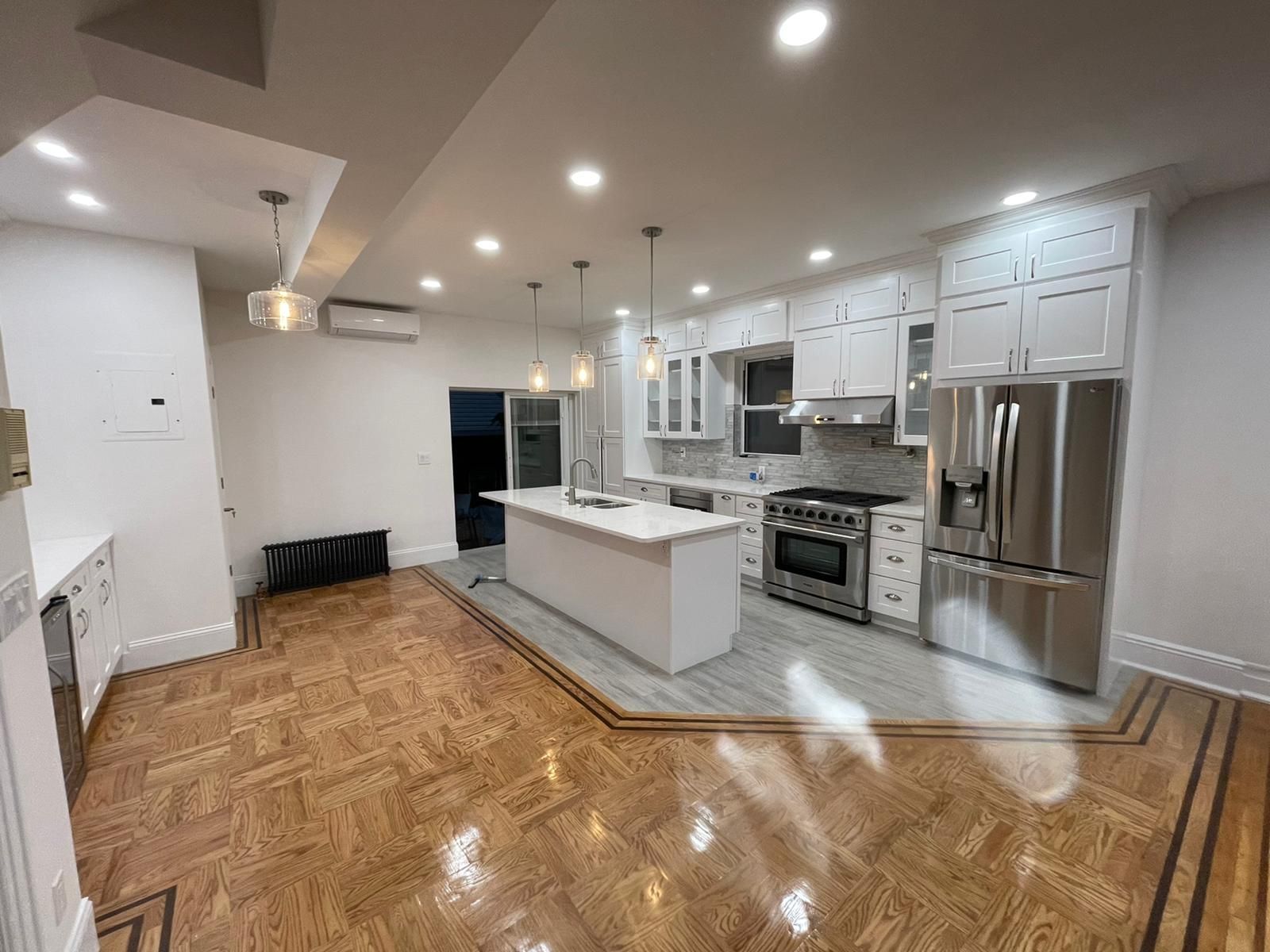 A kitchen with white cabinets and stainless steel appliances and a wooden floor