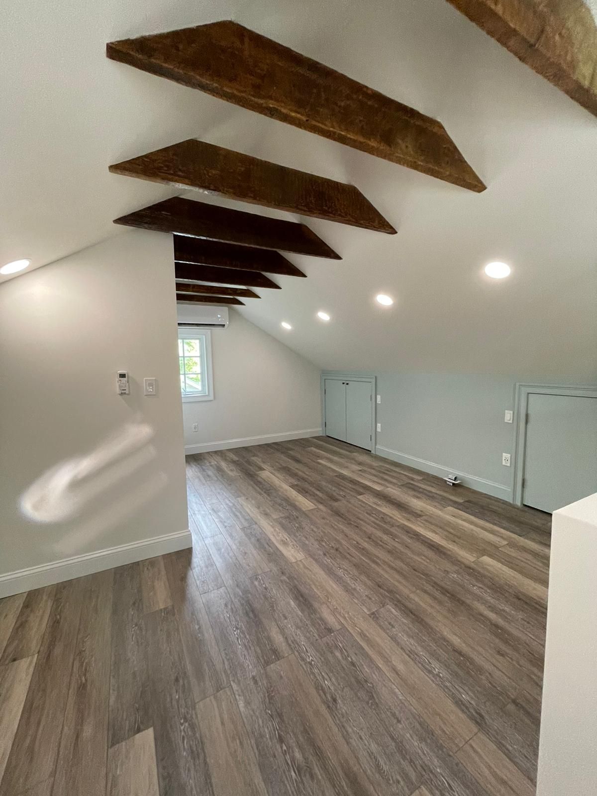 An empty room with wooden floors and beams on the ceiling