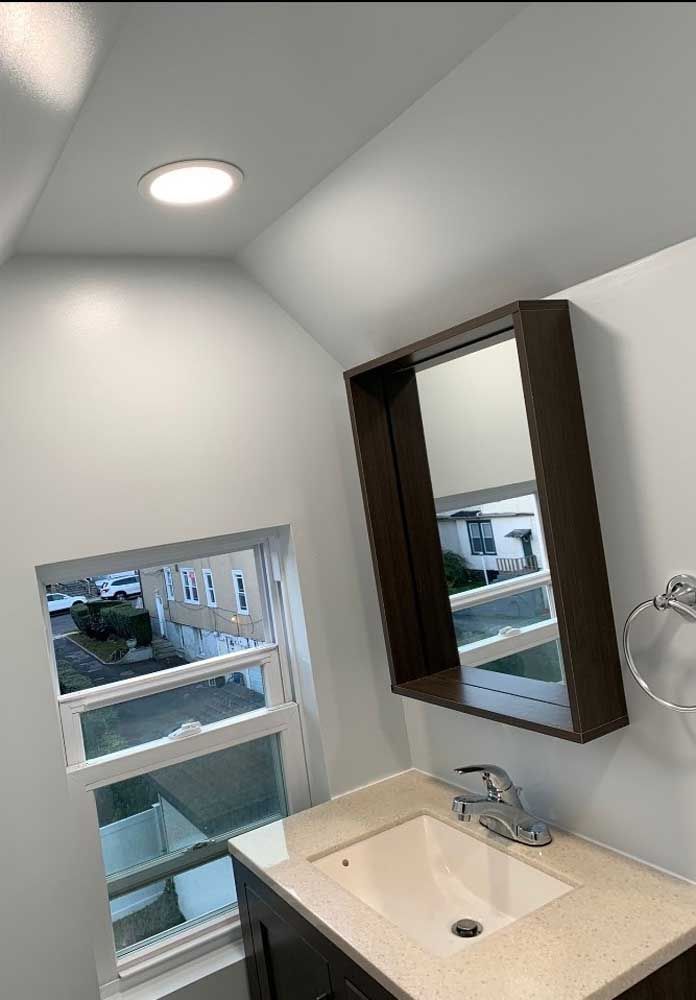 A bathroom with a sink, mirror and window