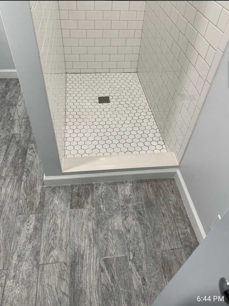 A bathroom with a walk in shower and a tiled floor