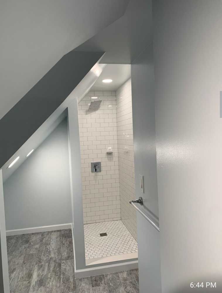 A bathroom with a walk in shower and a slanted ceiling