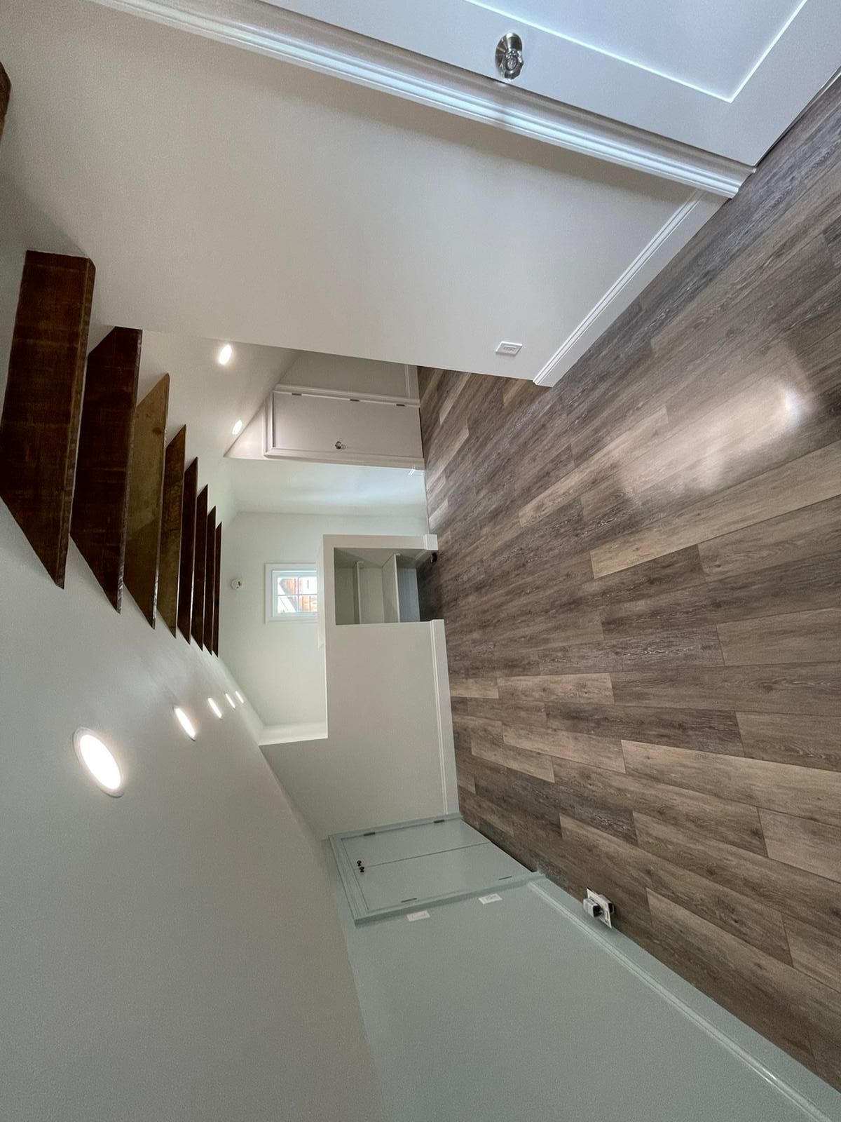 A bathroom with a wooden floor and stairs leading up to the second floor