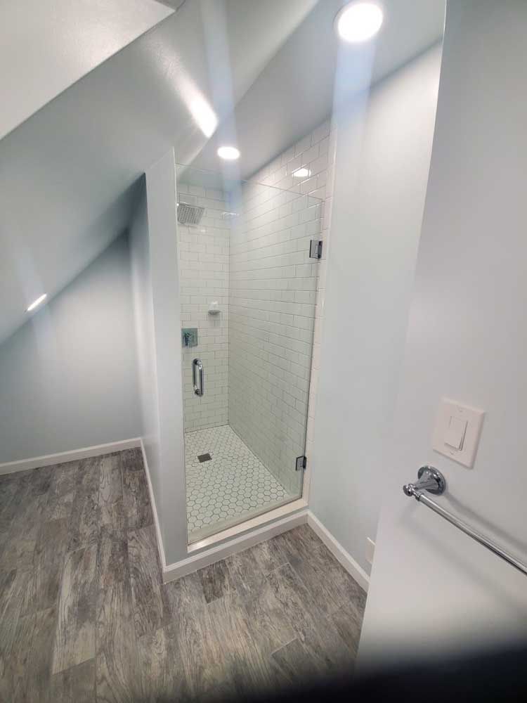 A bathroom with a walk in shower with a glass door