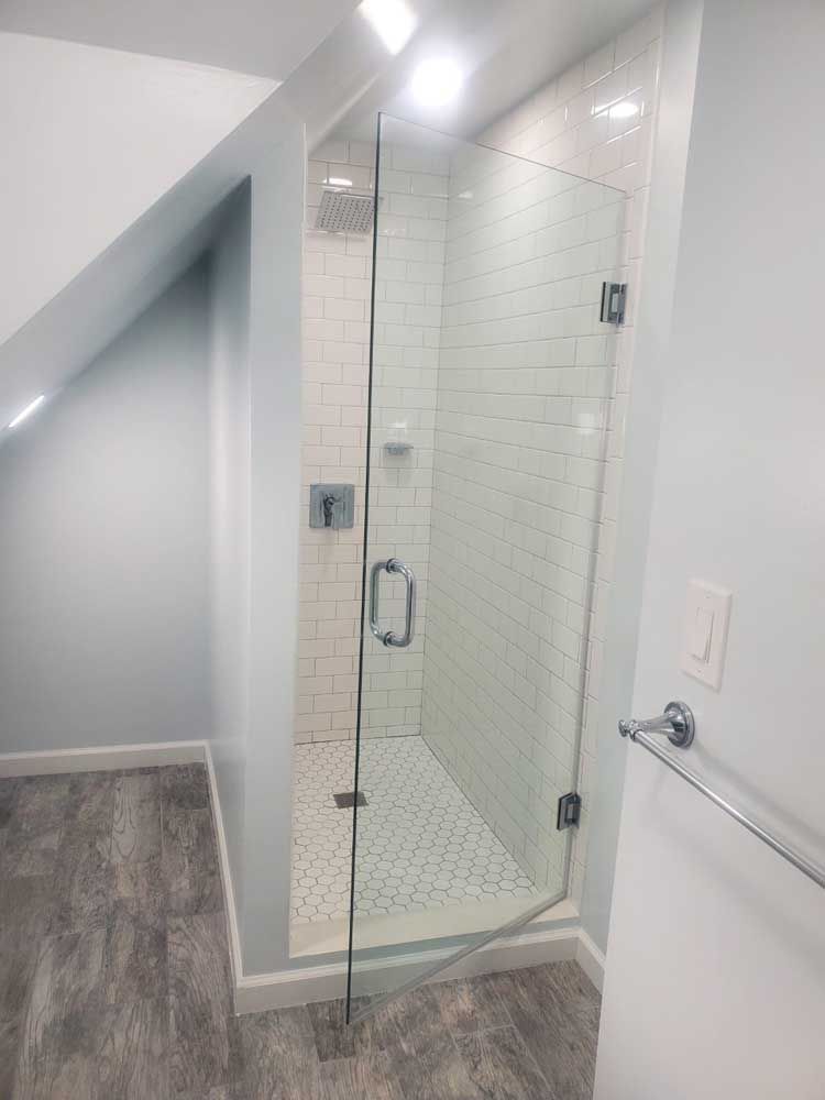 A bathroom with a walk in shower with a glass door