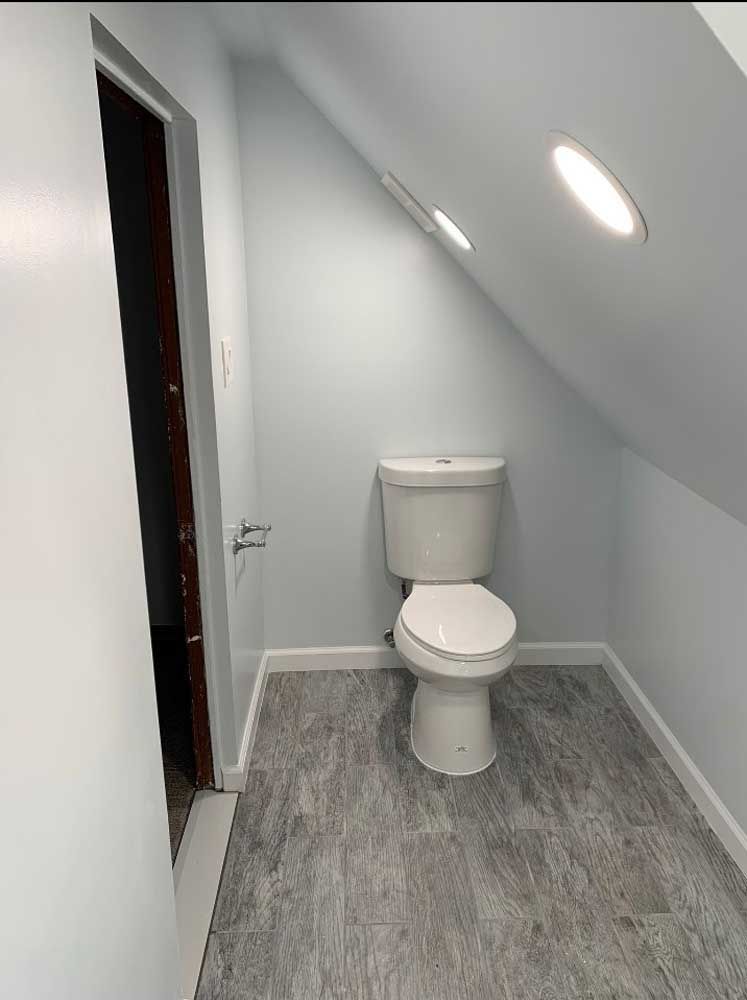 A toilet in a bathroom with a slanted ceiling