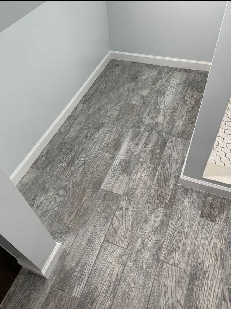 A bathroom with a gray tile floor and white trim
