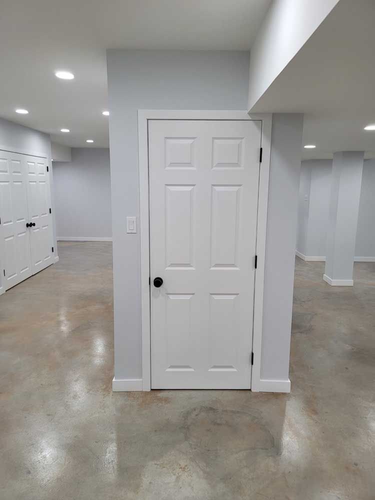 A basement with a white door and a concrete floor