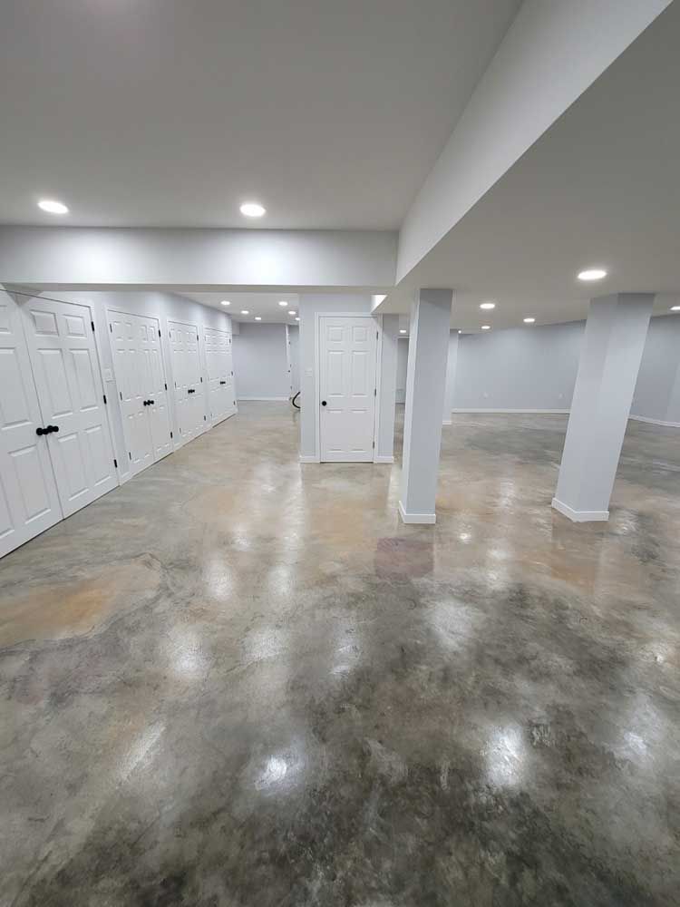 A large empty basement with concrete floors and white doors