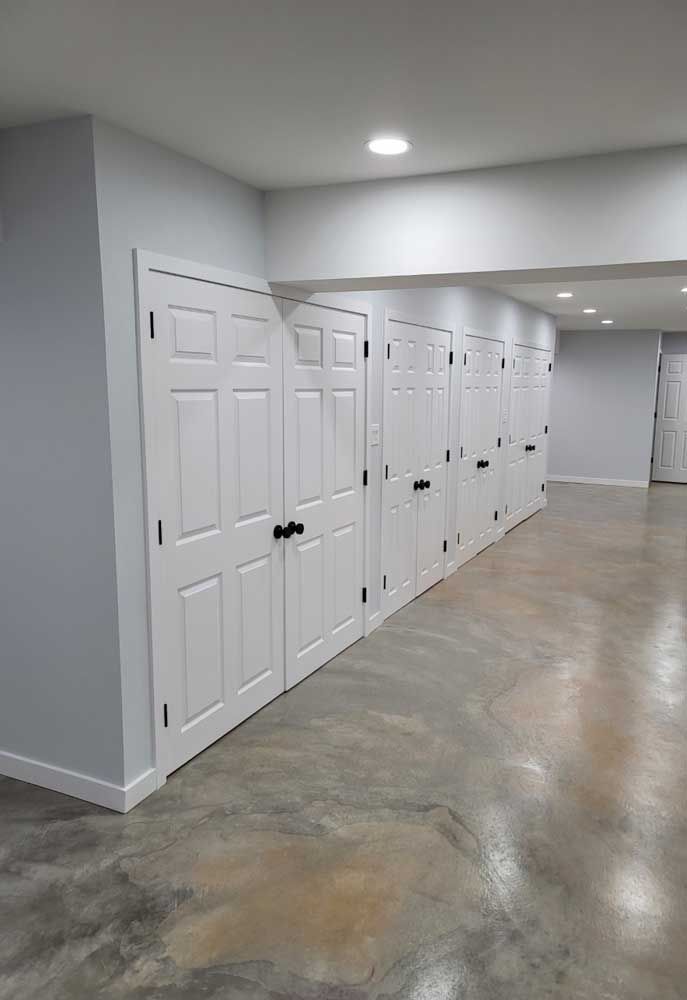 A row of white doors in a basement with a concrete floor