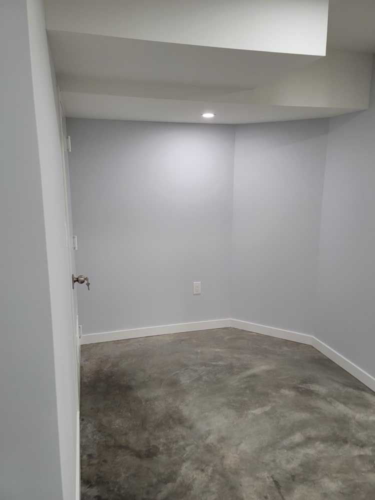 An empty room with a concrete floor and white walls