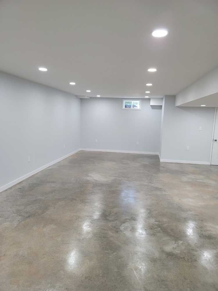 An empty basement with a concrete floor and white walls