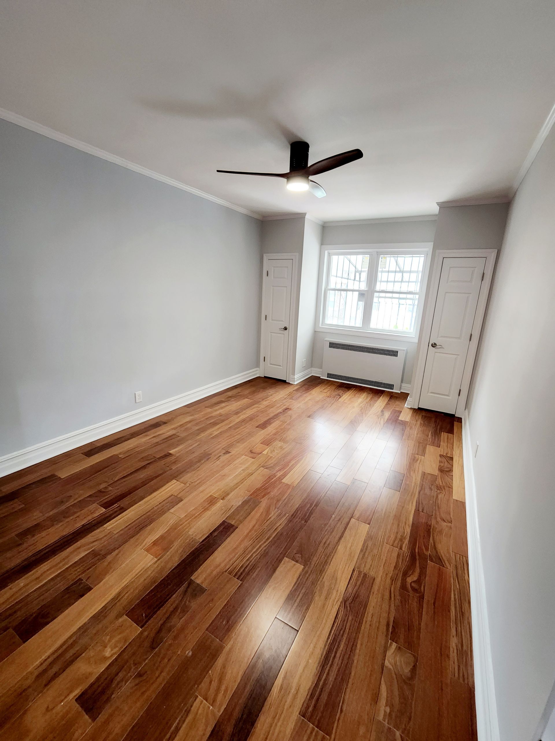 An empty room with hardwood floors and a ceiling fan