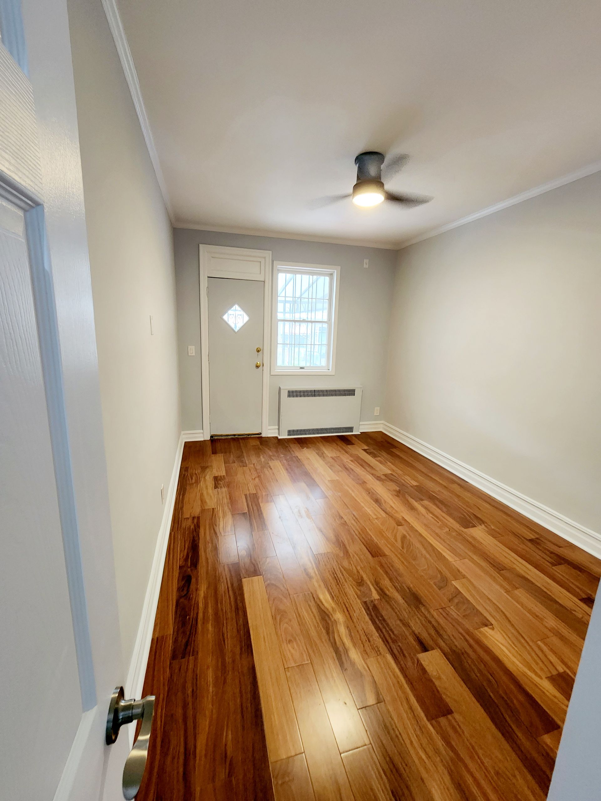 An empty room with hardwood floors and a ceiling fan