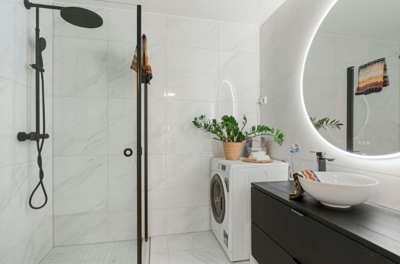 An attic space featuring light hardwood floors, white wooden support beams, and slanted ceilings with skylights.