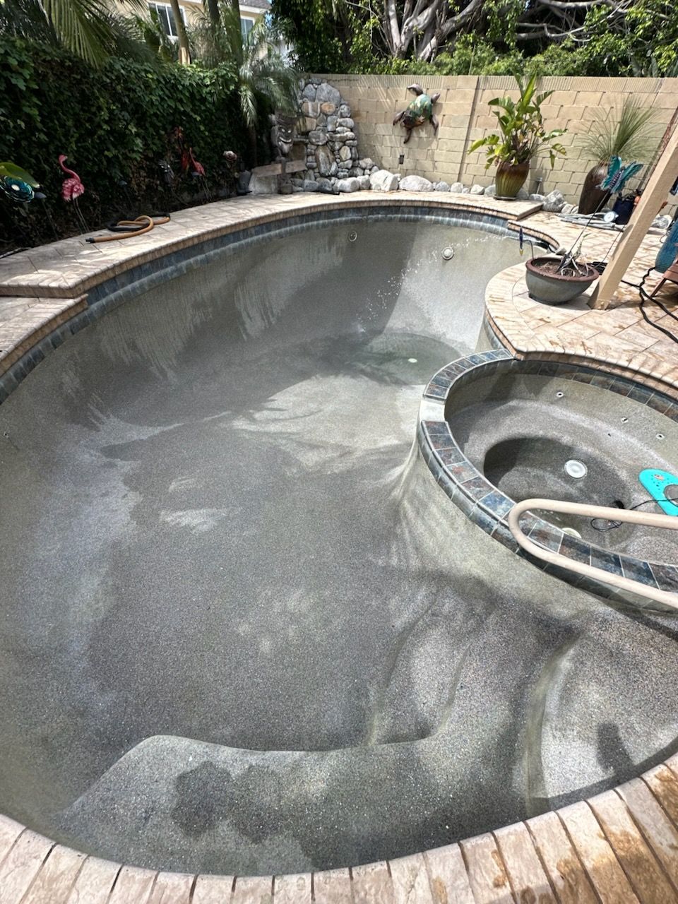 Pool cleaner skimming a backyard pool beside a stone wall and text reading “New home and pool?”