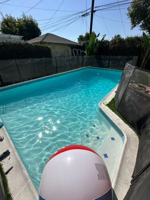 Backyard swimming pool with clear blue water and a red-and-white float in the foreground
