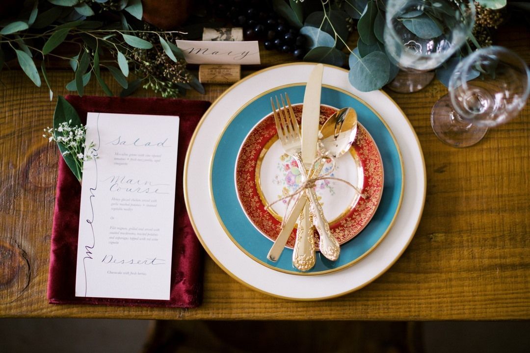 colorful place setting on a table with a printed menu in fancy font and a placecard with a name.