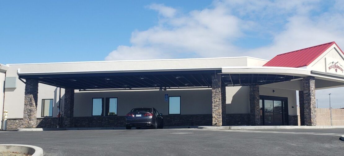 A car is parked in front of a building with a red roof.