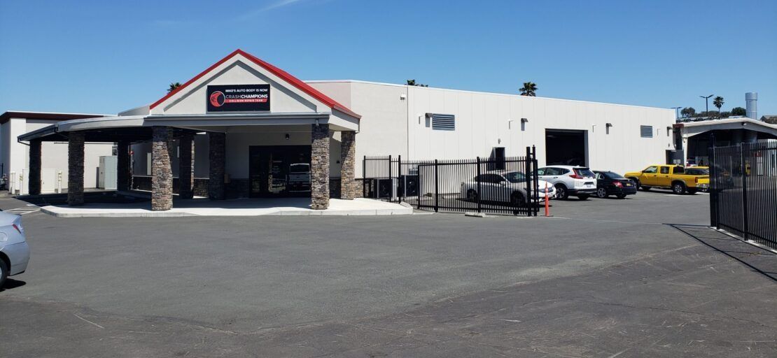 A large white building with a red roof and cars parked in front of it.