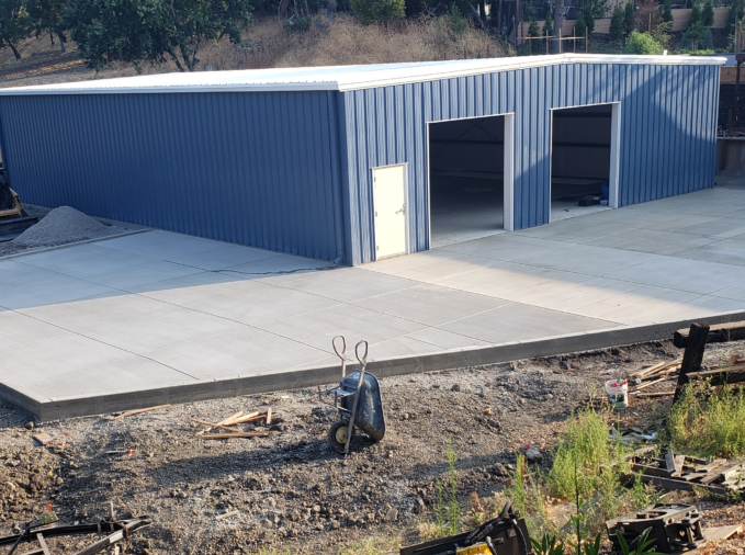A large metal building with a concrete driveway in front of it.