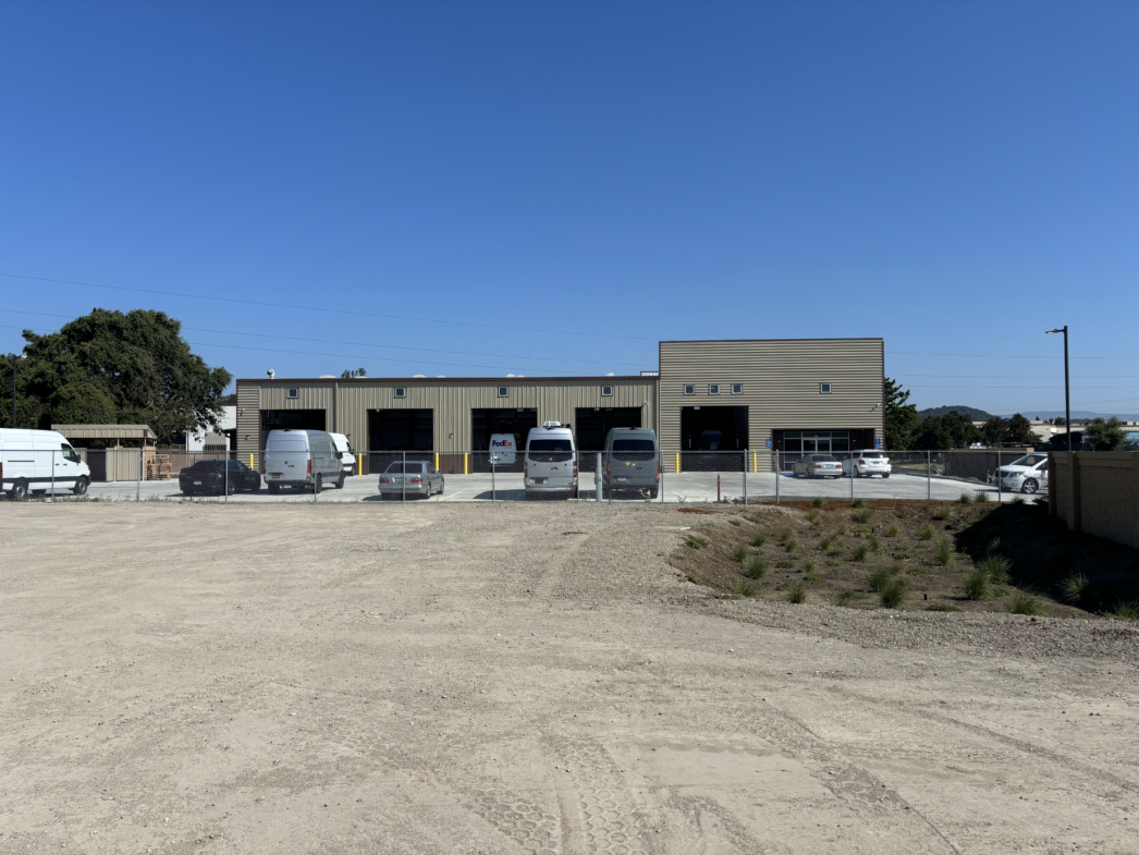 A row of vans are parked in front of a building.