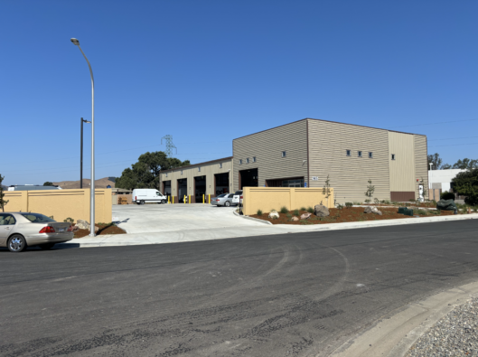 A white car is parked in front of a large building