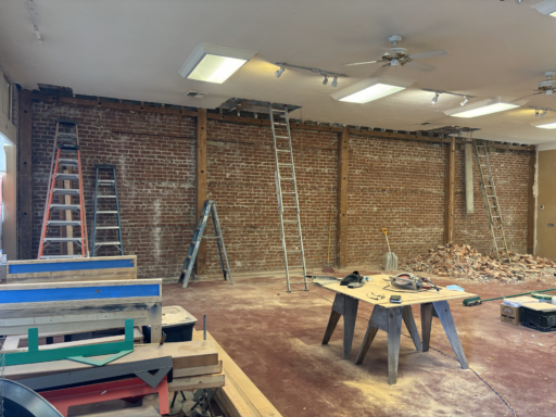 A large room with a brick wall and a ladder.