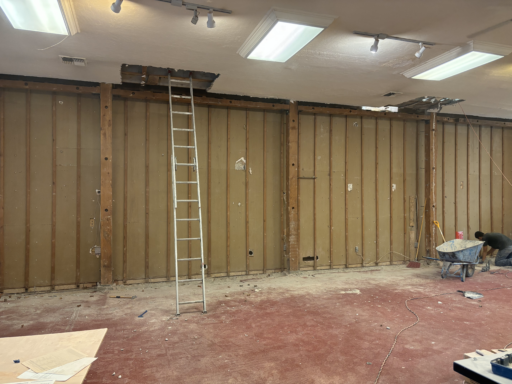 An empty room with a ladder and a wheelbarrow in it