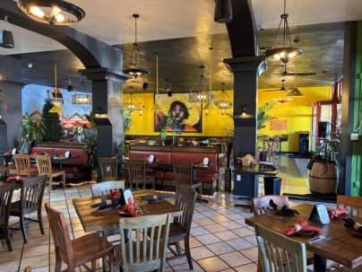 A restaurant with tables and chairs and a yellow wall.