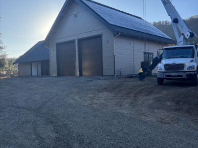 A white truck is parked in front of a building with solar panels on the roof.