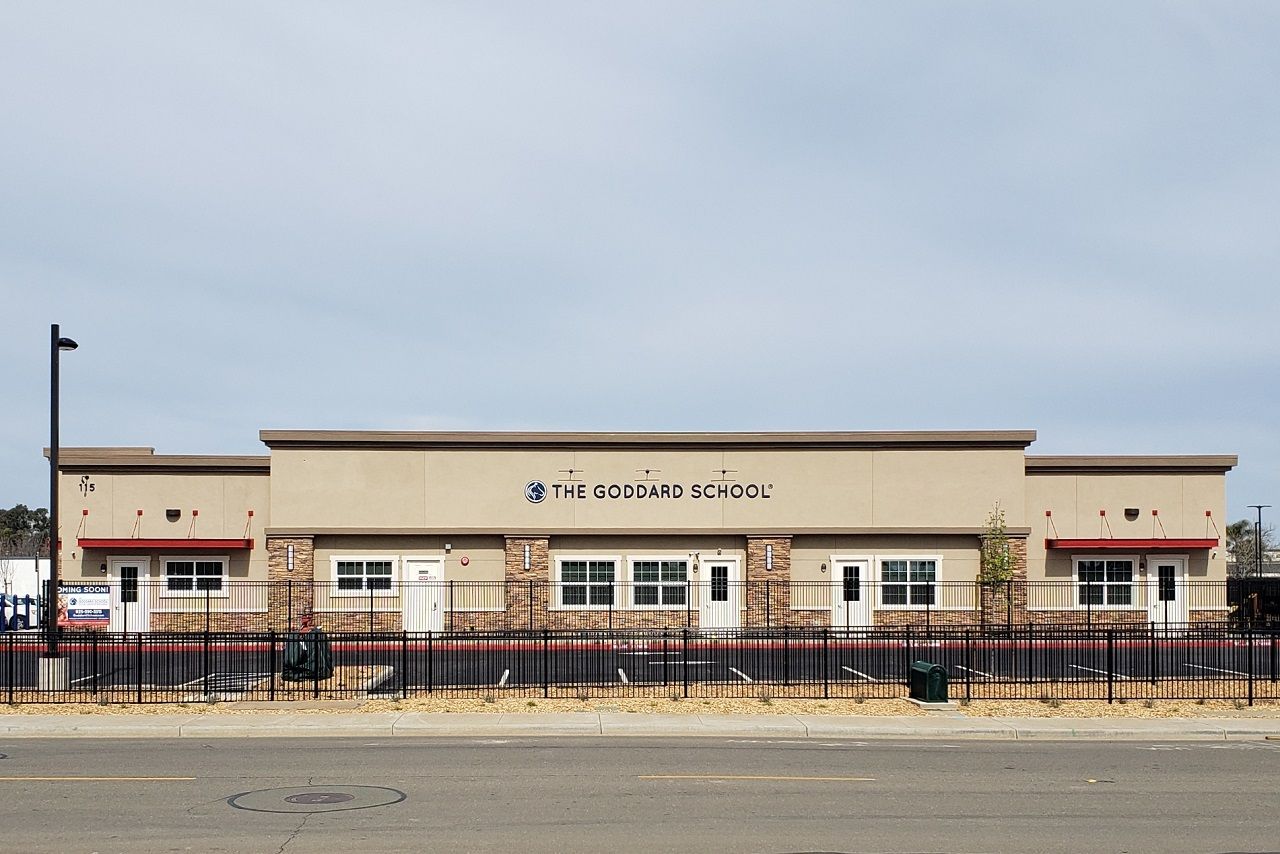 A large building with a fence around it is sitting on the side of the road.