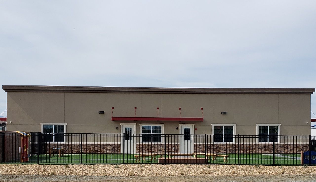 A large building with a fence around it and a picnic table in front of it.