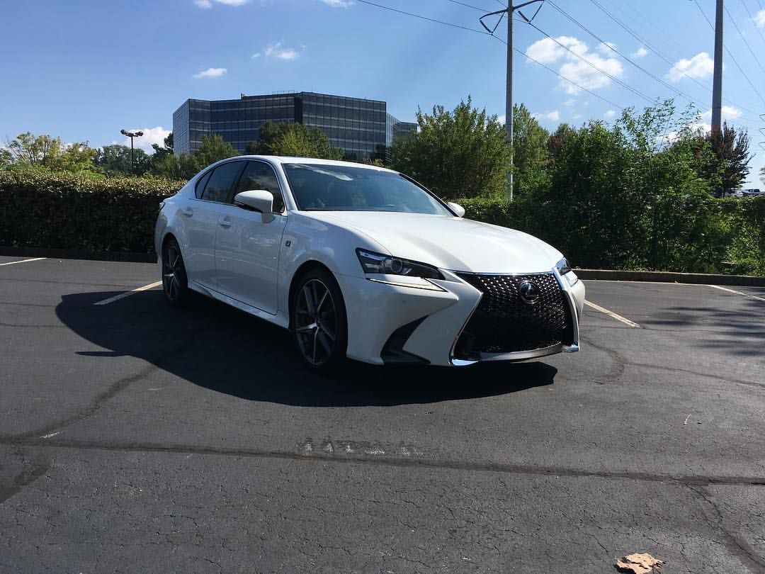 White Lexus sedan parked on asphalt. Black grille and wheels, sunny outdoor setting.