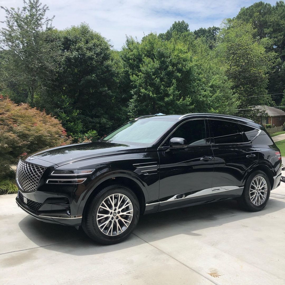 Black Tesla Model 3 parked in front of a brick building with garage doors.