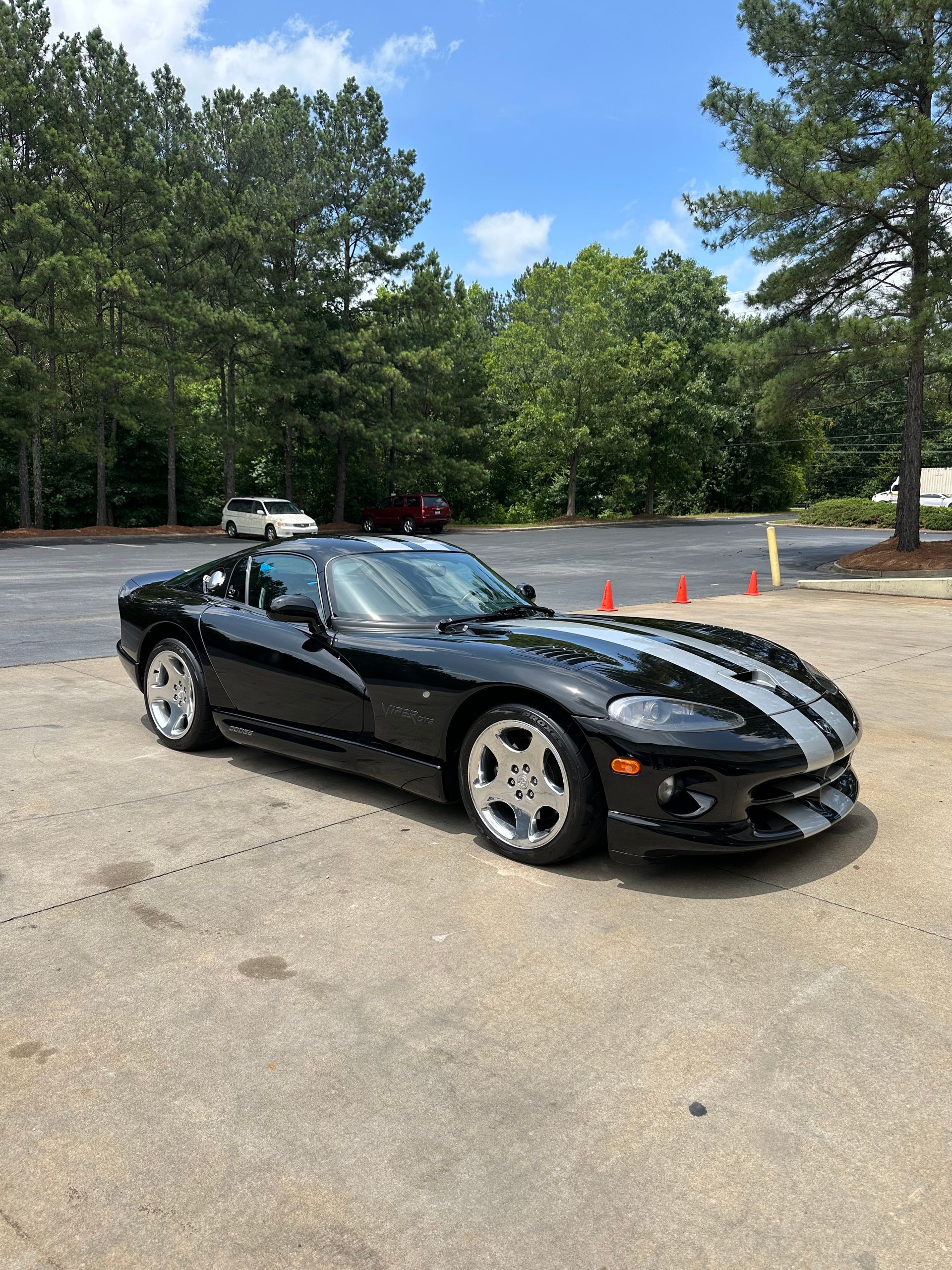 A person wearing black gloves is polishing the hood of a red car.