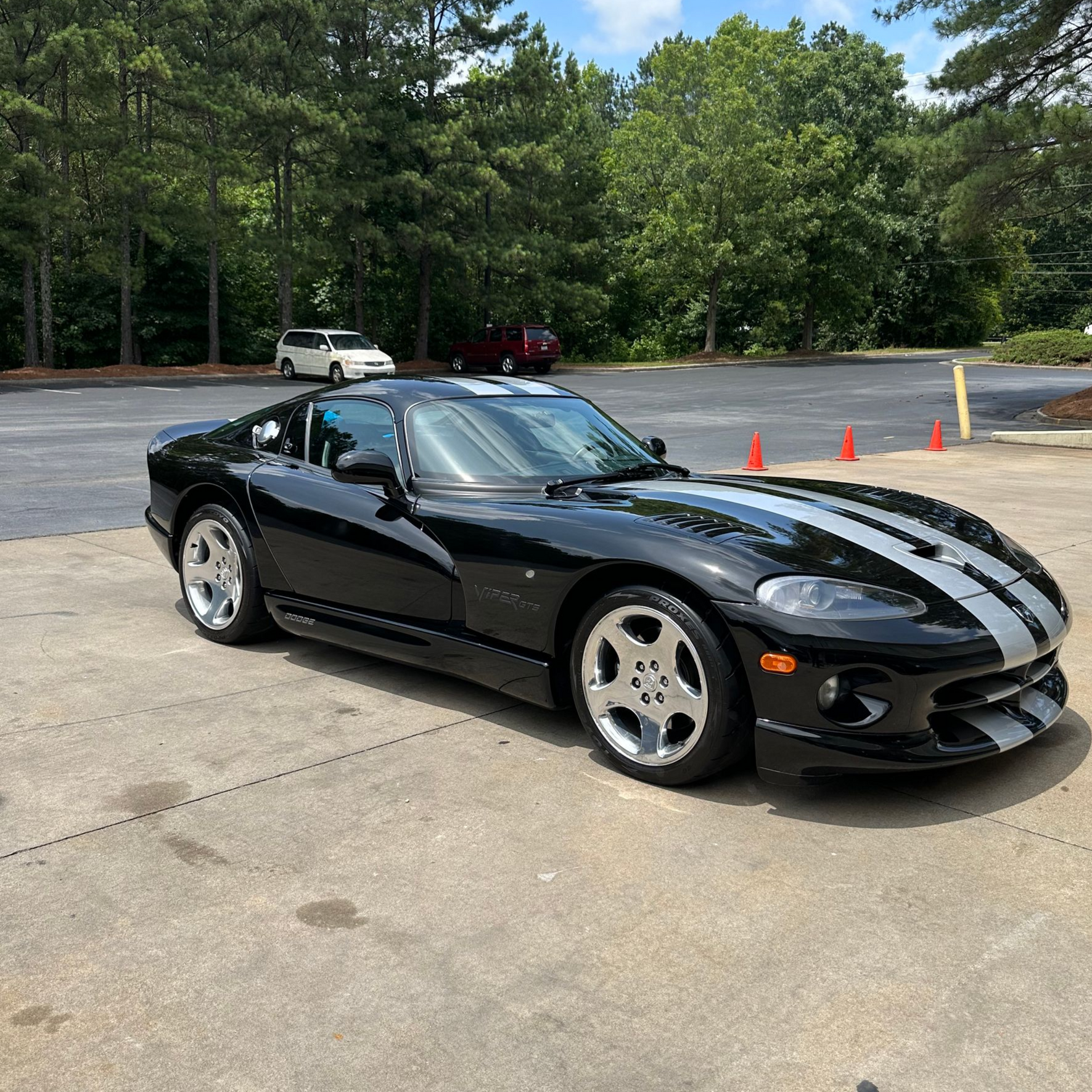 Black Dodge Viper with silver stripes parked on concrete.