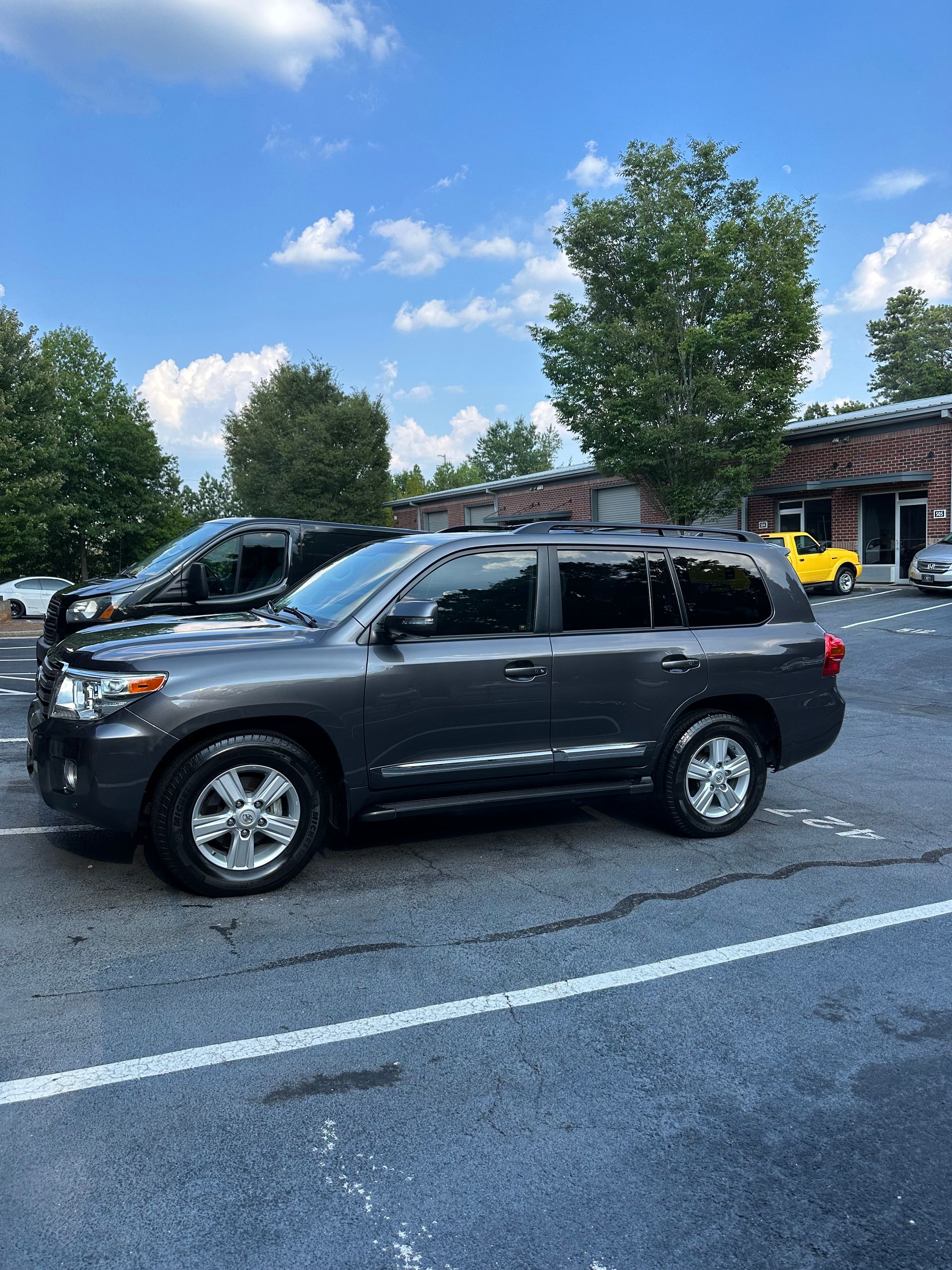 Gray Toyota Land Cruiser parked in a lot under a partly cloudy sky.