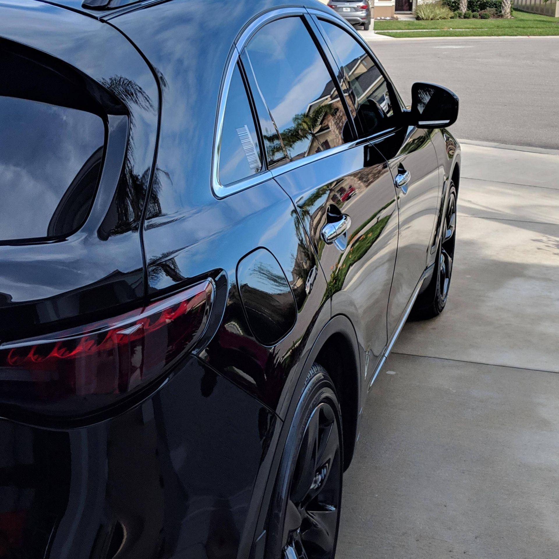 Black Infiniti SUV with tinted windows parked on a driveway.