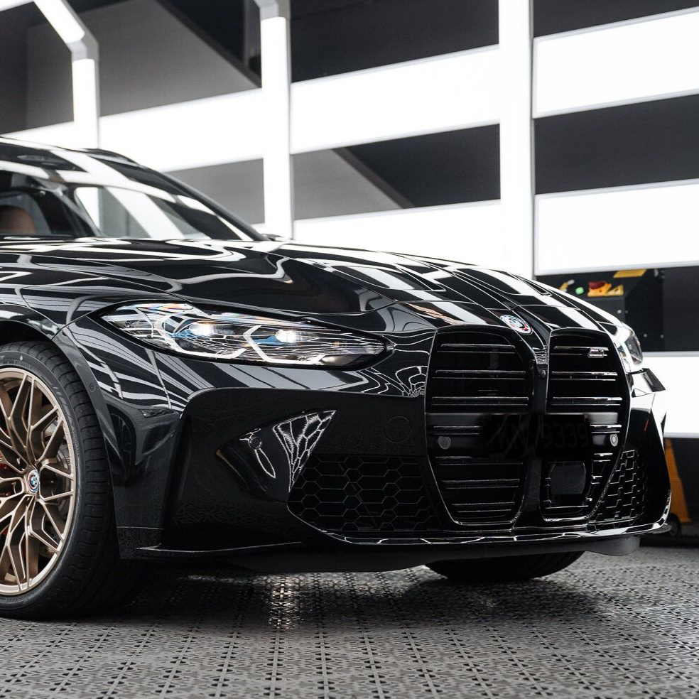 Black BMW M3 with bronze rims parked in a brightly lit studio.