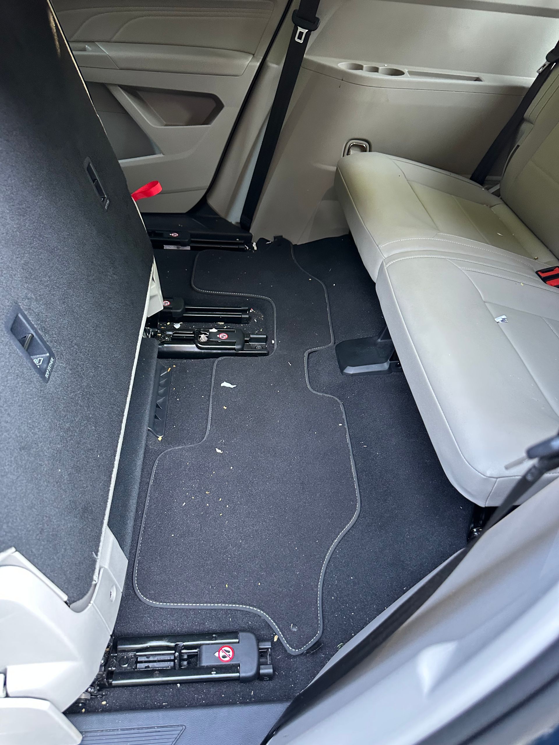 Back interior of a car with rear seats folded down, revealing a carpeted floor.