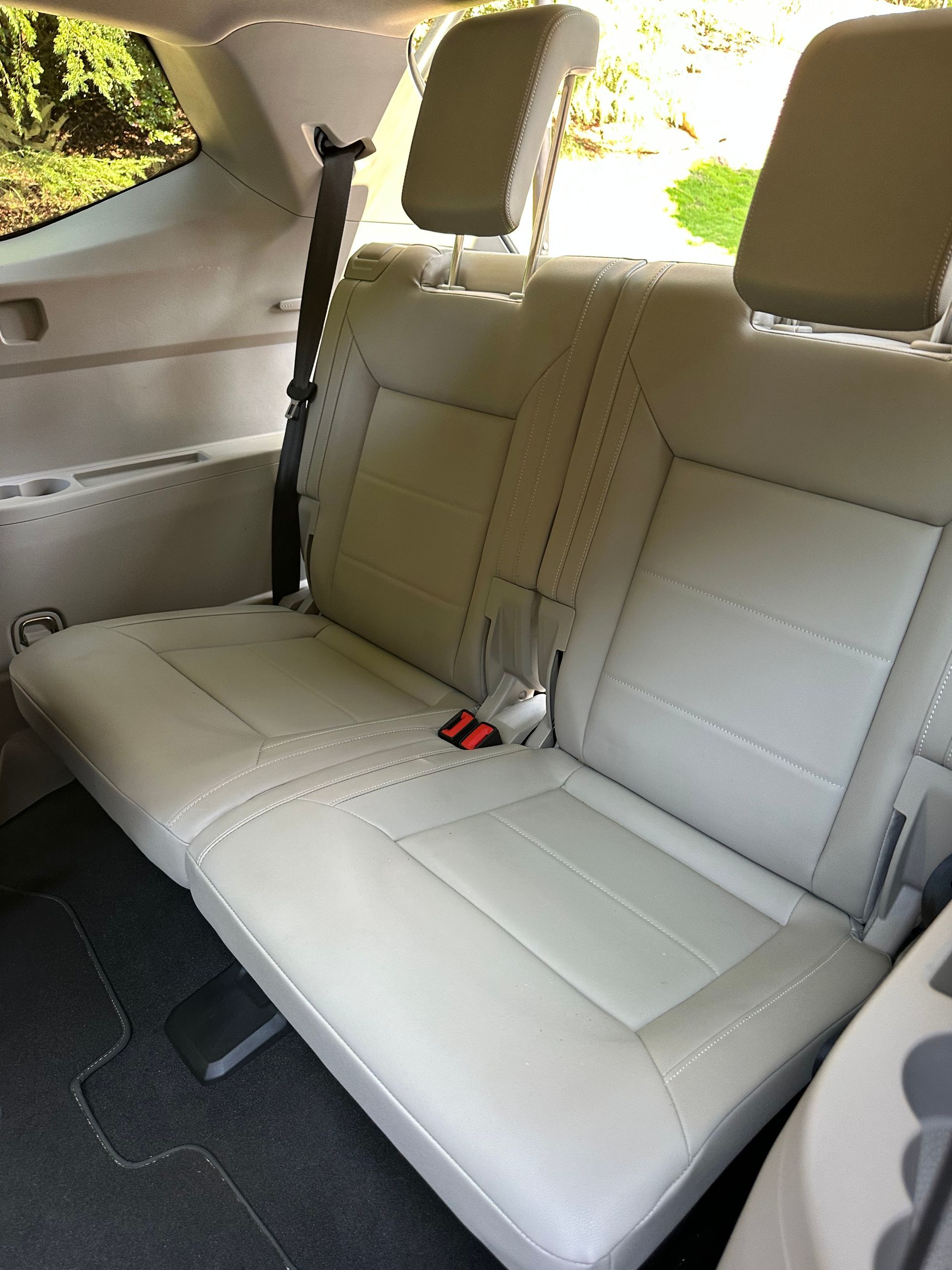 Beige leather car seats in the back row. Seatbelts are visible.