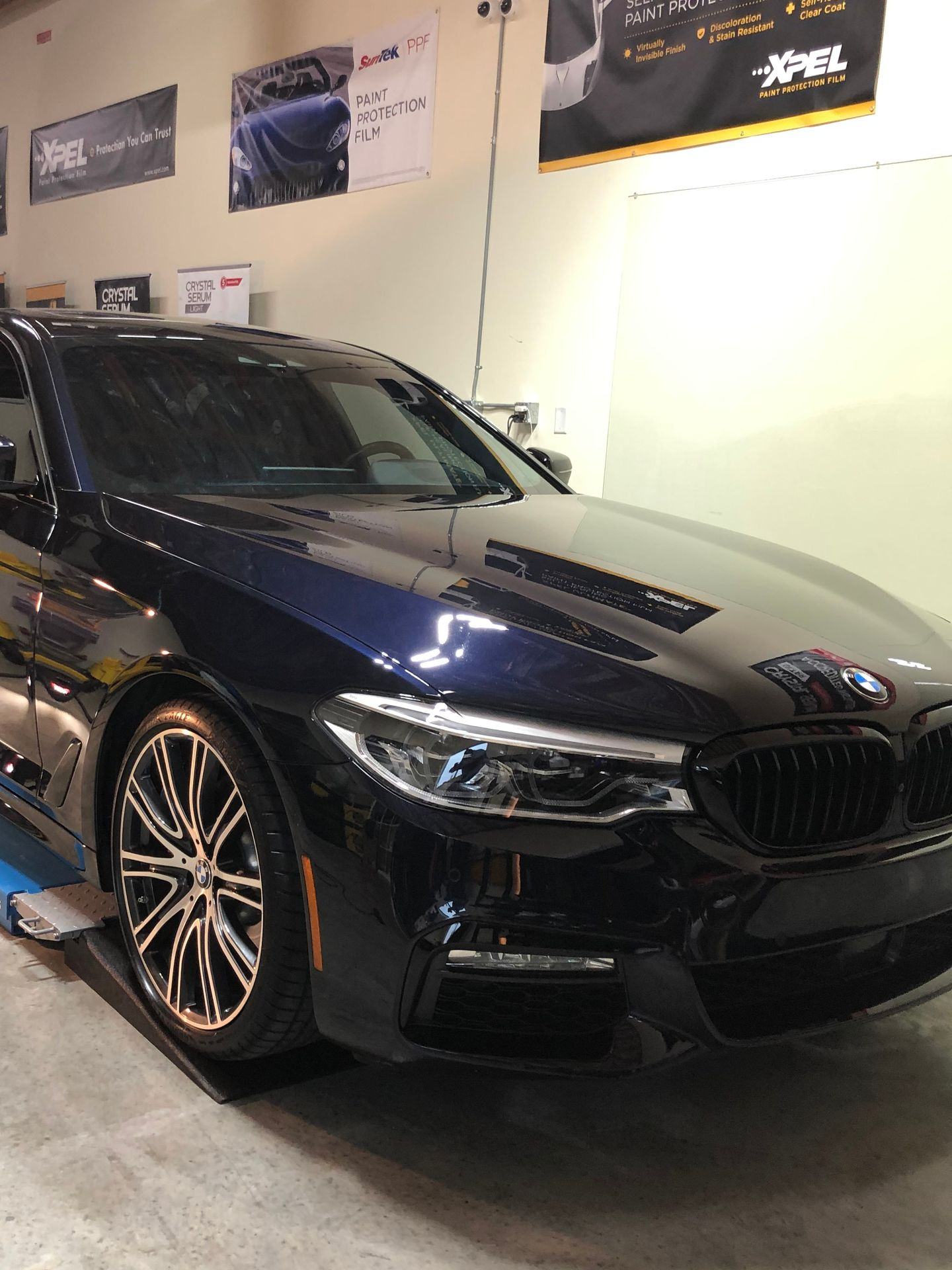 Dark blue BMW sedan in a shop with black grille and wheels.