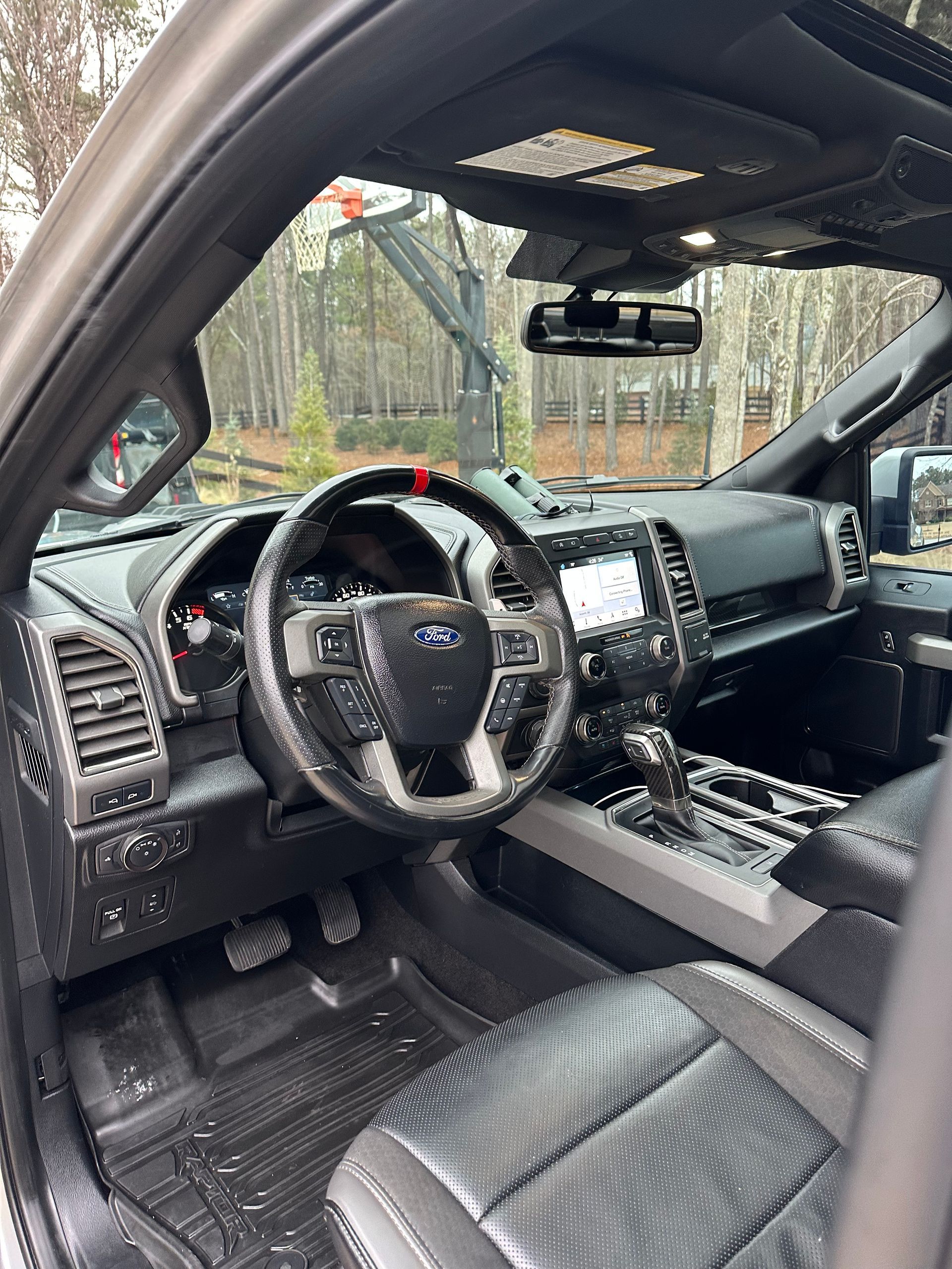 Interior view of a Ford truck with black leather seats, dashboard, and steering wheel, with red stripe on the steering wheel.