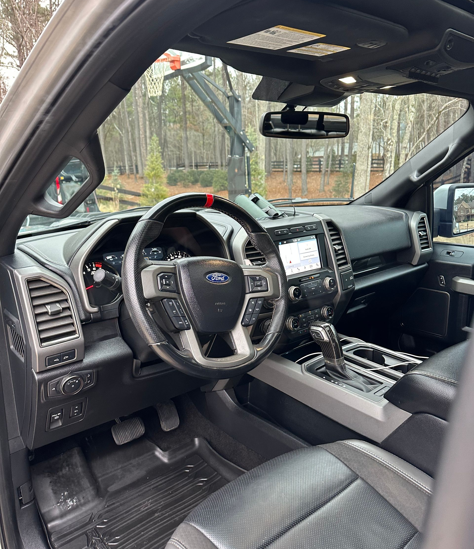 Interior view of a black Ford truck with a steering wheel, dashboard, and seats. Exterior visible through the windshield.