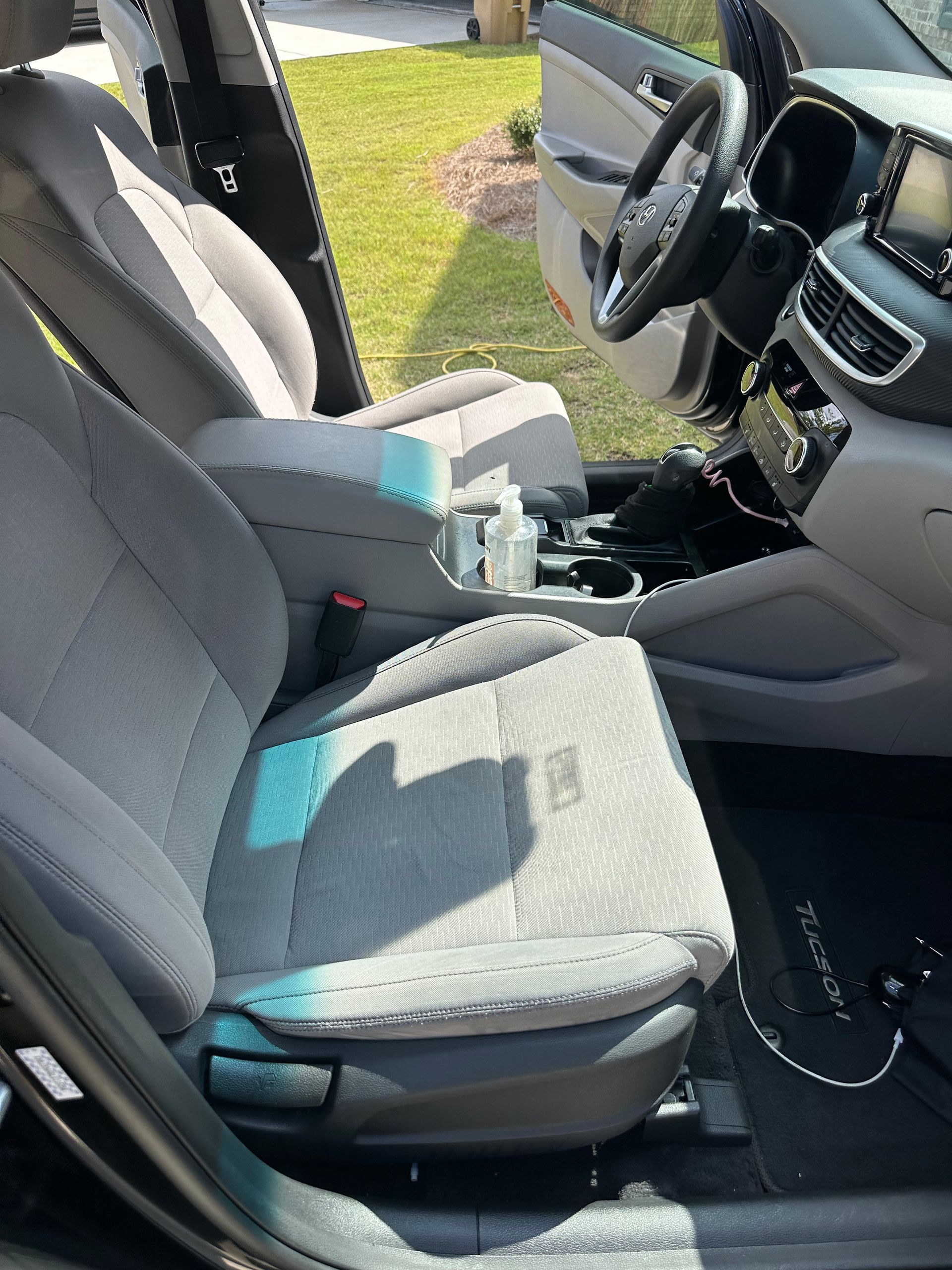 Gray cloth car seats in the front interior of a Hyundai Tucson with the door open.