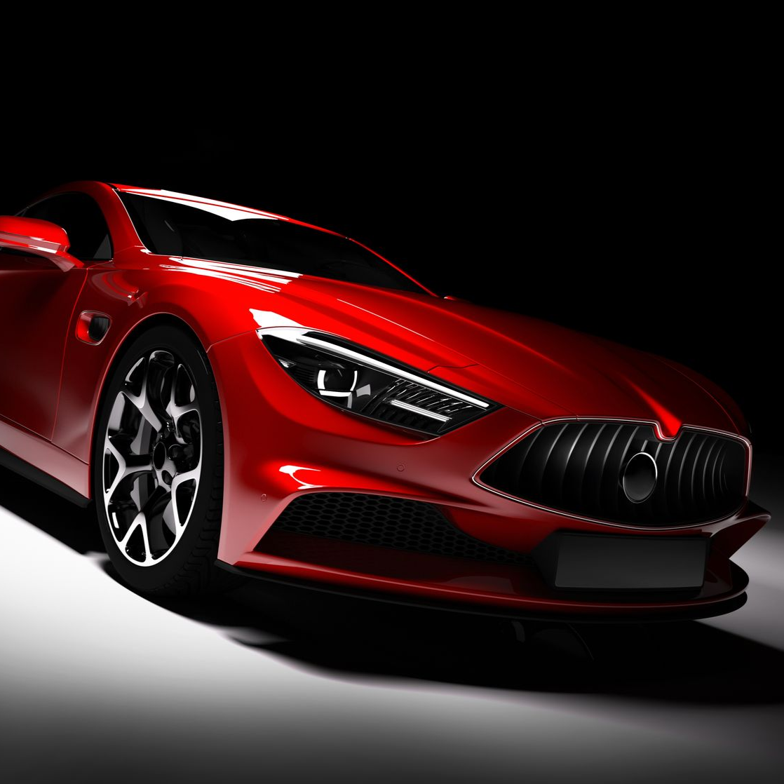 Red sports car with black wheels against a black background.