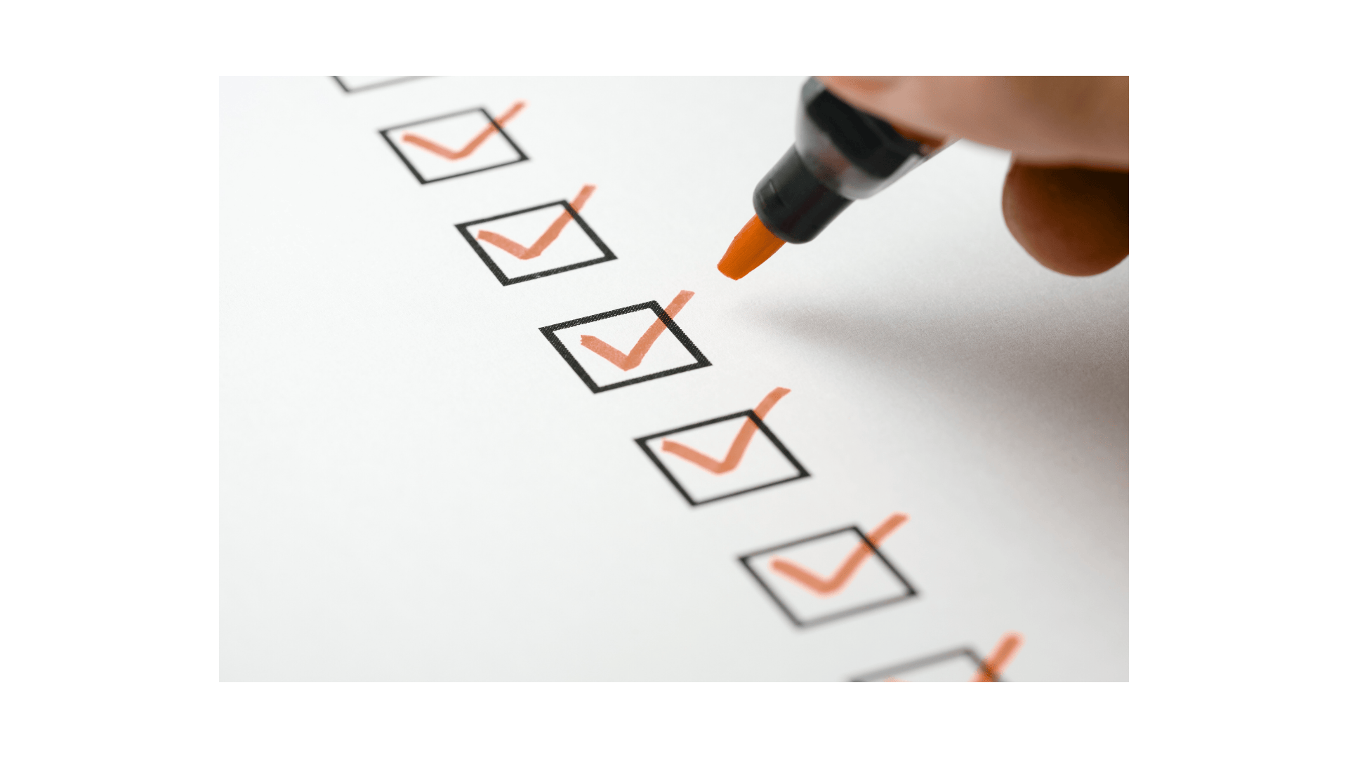 Cocher des cases à la main sur un papier blanc avec un marqueur orange.