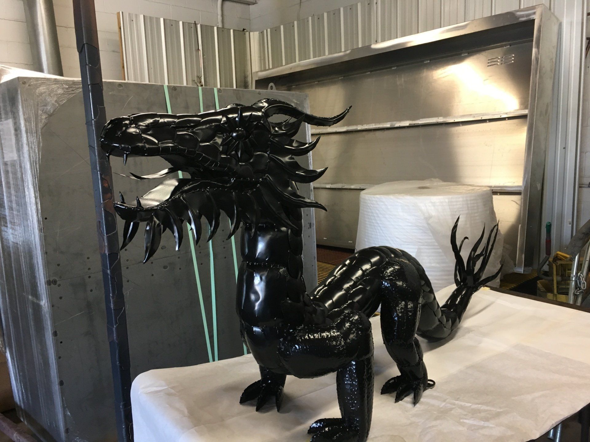 A black dragon statue is sitting on a white table.