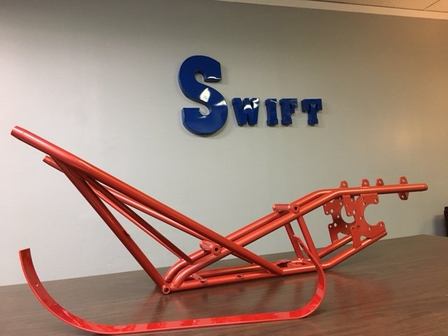 A red sled sits in front of a sign that says swift